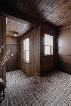 an empty room with brick floor and wood paneling on the walls is pictured in this image