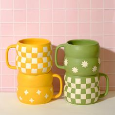 two green and yellow mugs sitting next to each other on a white counter top