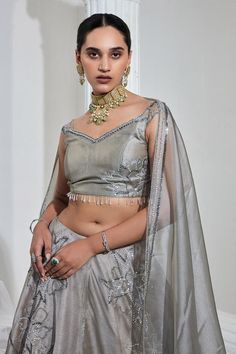 Metallic grey attached cancan lehenga with cutdana and sequin embroidery in floral pattern. Paired with an off-shoulder all over embroidered padded blouse and embroidered dupatta with tassel details. 
Components: 3
Pattern: Embroidered
Type Of Work: Sequin, Cutdana
Neckline: Sweetheart
Sleeve Type: Sleeveless
Fabric: Metallic Organza
Color: Grey
Other Details: 
Attached lining
Length: 
Lehenga: 43 inches
Blouse: 13.5inches
Occasion: Sangeet - Aza Fashions Silver Embellished Organza Lehenga, Embellished Silver Organza Lehenga, Silver Pre-draped Saree With Resham Embroidery For Wedding, Fitted Silver Sharara With Intricate Embroidery, Silver Pre-draped Saree With Resham Embroidery For Reception, Silver Organza Lehenga With Zari Work, Designer Silver Organza Lehenga, Designer Silver Choli With Sheer Dupatta, Silver Semi-stitched Pre-draped Saree For Wedding