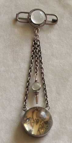 This is a rare example of a women's Chatelaine Watch pin. It is made of lower grade silver (less than 925 parts per 1000) and is not marked but has been tested., The brooch length is 5 1/2 inches from the top of the pin to the bottom of the ball watch. The top pin is 2 inches across and 9/16 inch at its widest. The ball watch is 1 1/8 inches across. The dial has some hairline cracks and is marked G.H. Oudin Palais Royal 52. The movement appears to be French as well. This watch is working and has its ball topped key for winding and setting. There are plenty of surface scratches on the glass balls, but no deep gouges, cracks or chips.C. 1860 and French. A true survivor! Follow me on instagram@jettesjewels. Elegant Silver Medallion Brooch, Antique Pendant Brooch For Formal Occasions, Antique Pendant Brooches For Formal Occasions, Victorian Formal Jewelry With Oxidized Finish, Classic Silver Brooch, Antique Metal Brooch For Formal Occasions, Sterling Silver Pendant Brooch For Formal Occasions, Formal Sterling Silver Pendant Brooch, Silver Engraved Brooches For Formal Occasions