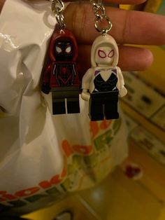 a person holding two legos in their hands, one spiderman and the other female