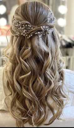 the back of a woman's head with long wavy hair and flowers in her hair