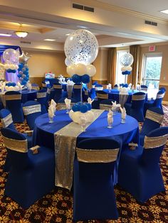 a room filled with blue and white tables covered in balloons, silver chairs and tablecloths