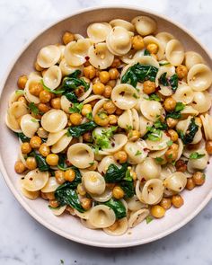 pasta with spinach and chickpeas in a white bowl on a marble surface