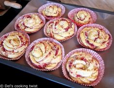 many pastries are in pink paper cups on a baking sheet with powdered sugar