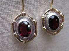 Stunning red Garnet Earrings with 14k solid Gold frame and 14k solid Gold .8 mm ear wires.  Finished with safety clasp so you'll never lose this precious pair.  The  Garnet gemstones measure 8 x 6 mm.  The gemstones sit in a  Sterling Silver oval frame for the finishing touch.   Garnet is a spiritual stone of self-empowerment.  This gemstone imbues the owner with strength, safety and prosperity.   Garnet is the January birthstone and the gemstone that celebrates the two year marriage anniversary. Formal Oval Earrings With Bezel Setting, Formal Oval Bezel Set Earrings, Elegant Oval Earrings With Bezel Setting, Formal Garnet Jewelry With Bezel Setting, Oval Fine Jewelry Earrings With Bezel Setting, Gold Garnet Jewelry With Bezel Setting, Classic Garnet Jewelry With Polished Finish, Heirloom Pierced Jewelry For Formal Occasions, Heirloom Style Pierced Jewelry For Formal Occasions