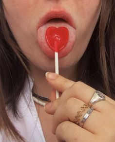 a woman holding a red heart shaped lollipop