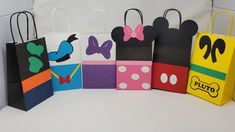 mickey mouse bags are lined up in different colors and shapes, with bows on them