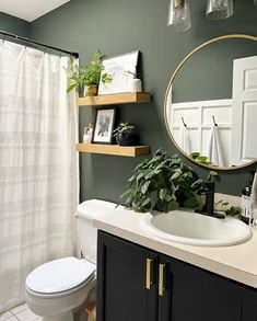 a white toilet sitting under a bathroom mirror next to a sink and a shower curtain