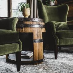 a wooden barrel table sitting on top of a rug next to a chair and ottoman