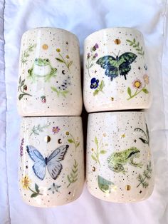 four ceramic cups with butterflies and flowers painted on them