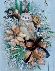 an owl sitting on top of a christmas wreath with pine cones and other holiday decorations