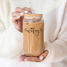 a woman holding a jar filled with liquid and a straw in it's hand