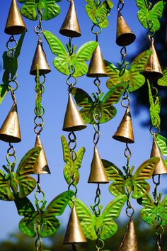 a bunch of bells that are hanging in the air with green leaves on them,