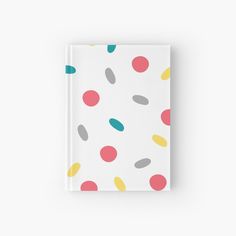 a white notebook with multicolored polka dots on the front and back cover, sitting against a white background