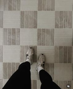 a person standing on a tile floor with their feet up in front of the camera