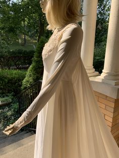 a woman in a white dress is standing on the porch with her arms out to the side