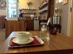 a coffee cup and saucer sitting on a wooden table in a small room with shelves