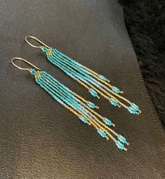 "Maui Swan Designs beautiful, delicate earrings. Czech glass seed beads hand sewn with nylon thread, 3\" long, 3/8\" wide. Original design, incorporates iridescent, opaque and transparent seed beads. Beautiful & bold tones of dark teal, turquoise and gold. Handmade 14K gold-filled clasp. These are stunning & tiny enough u won't feel them on your ears but they are super shiny!!" Turquoise Earrings With Gold Beads, Handmade Gold Beaded Long Drop Earrings, Chain Fringe, Sea Sand, Turquoise And Gold, Teal Turquoise, Wire Wrapped Earrings, Seed Bead Earrings, Delicate Earrings