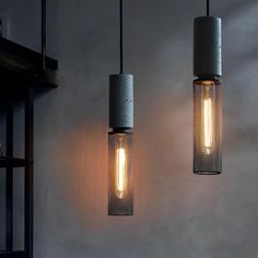 three light fixtures hanging from the ceiling in a room with concrete walls and flooring