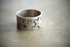 "All sorts of stars adorn this wide band. Three different styles of stars are stamped all the way around the ring with one star cutout in the center. The band measures about 3/8\". I gave it a more rustic aged look so there is texture from hammering and forming. I blackened the surface and polished it back up so all the layers and textures would be accented. Made in sterling silver. CURRENT LEAD TIME ON ALL ORDERS: 2 Weeks SHIP TIME TO US: 2-7 business days SHIP TIME OUTSIDE US: Up to 8 weeks (a Etched Silver Ring, Soldering Rings, Jewelry Links, Wide Silver Band, Visionary Fashion, Metal Jewelry Making, Simple Silver Jewelry, Dope Jewelry, Funky Jewelry