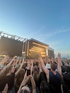 a large group of people at a concert with their hands in the air