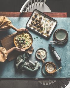 a person holding a plate with food on it next to other dishes and utensils