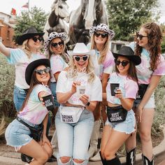 a group of women in cowboy hats and shirts posing for a photo with a horse statue behind them