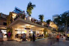 a group of people standing outside of a building with lights on the roof and balconies