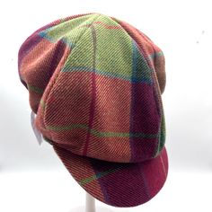 a red and green plaid hat sitting on top of a white mannequin head