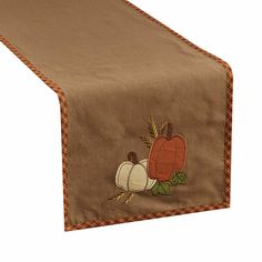 a table runner with pumpkins and gourds embroidered on the front, along with an orange ribbon