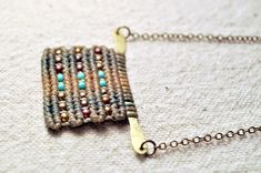 a close up of a chain with beads on it and a square shaped object in the middle