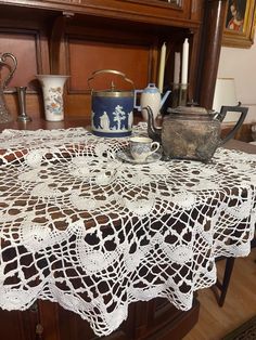 there is a doily on the table with teapots and cups in it