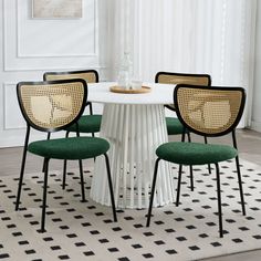 a white table with four green chairs around it and a rug in front of it