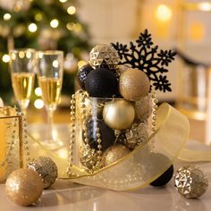 a table topped with gold and black ornaments next to two glasses filled with champagne flutes