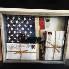 an american flag and some letters are in a shadow box that is decorated with twine