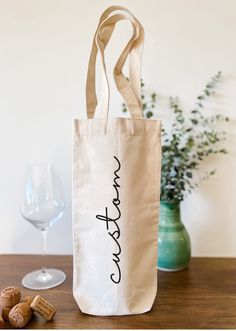 a tote bag sitting on top of a wooden table next to a wine glass