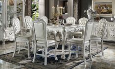 a white dining room table and chairs with chandelier in the middle of it