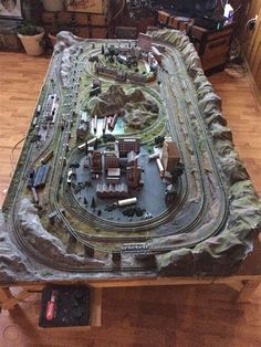 a model train set up on a table in a room with wooden floors and walls