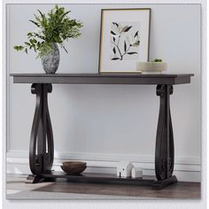 a wooden table with two vases on it and a plant in the corner next to it