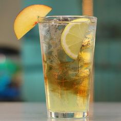 a glass filled with ice and lemon on top of a table next to a slice of apple