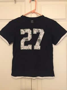 Gymboree Boys Navy Blue Sports Number 27 Layered Look T-shirt Jersey Sz 7 EUC. Condition is "Pre-owned". Shipped with USPS First Class. Navy blue with distressed white screen printed number 27. Decorative green stitching outlines the numbers. Shirt has a layered distressed look around the edges. Preowned in excellent condition. Minimal wash wear. Casual Sports T-shirt With Number Print, Crew Neck Top With Number Print For Sports Season, Blue Crew Neck T-shirt With Number Print, Cotton Tops With Number Print For Sports Season, Short Sleeve Tops With Number Print For Sports Season, Cotton Sports Tops With Number Print, Sports Tops With Number Print And Crew Neck, Short Sleeve Sports Top With Number Print, Casual Blue Tops With Number Print