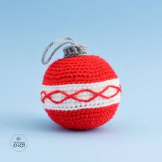 a crocheted red and white ball ornament on a light blue background