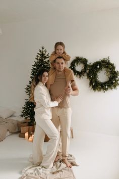 a man and woman standing on top of a bed in front of a christmas tree