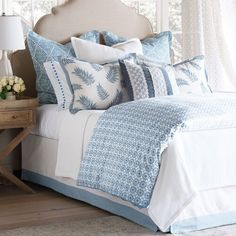 a bed with blue and white pillows on top of it