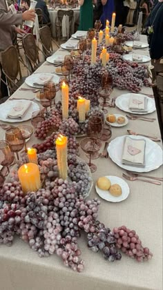 a long table with many plates and candles on it