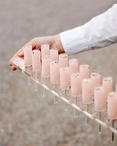 a person holding a tray filled with pink drinks