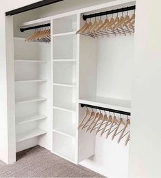 an empty closet with white shelves and wooden hangers