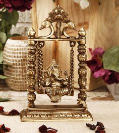 a golden ganeshi idol sitting on top of a table next to dried flowers