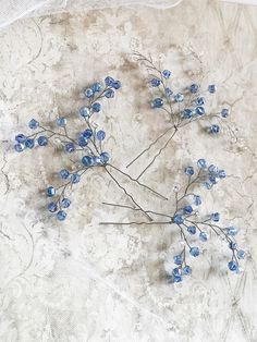 some blue flowers are sitting on a white table cloth and it looks like they have been made out of glass beads